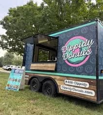 Dippidy Donuts concession trailer with an open serving window and a menu sign, parked on grass