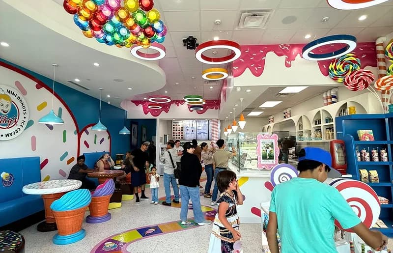 Niky's Mini Donuts and ice cream shop interior with candy-themed decor, colorful seating, and customers at the counter