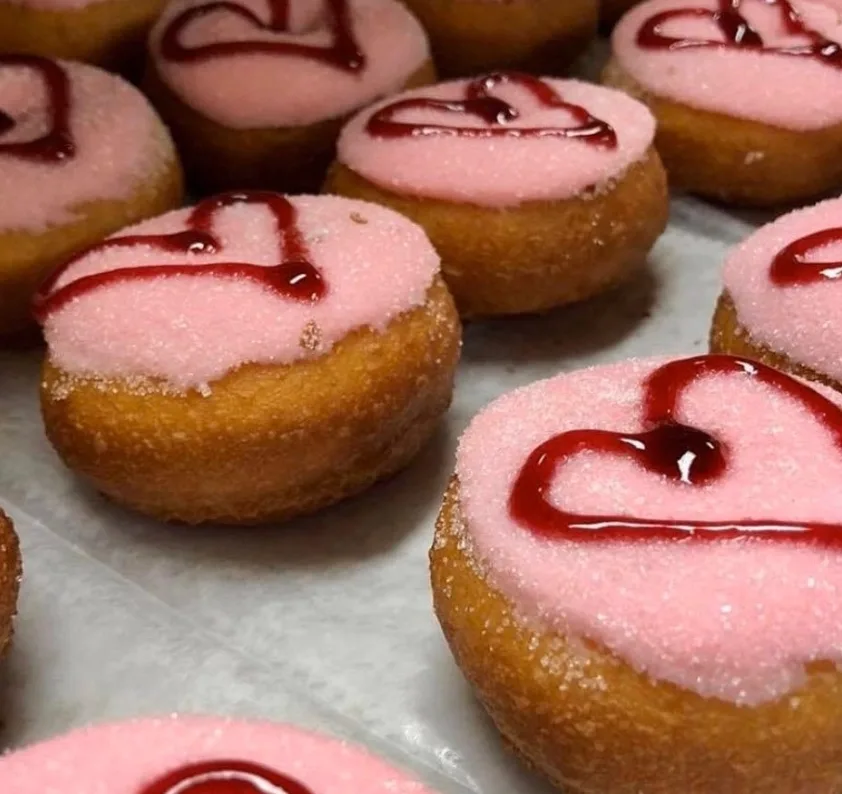 Peace, Love & Little Donuts donuts with pink sugar frosting and red heart-shaped drizzle