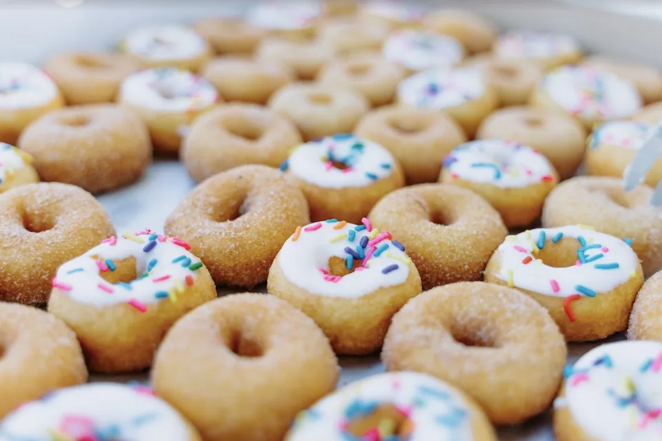 Tray of The Mini Donut Company mini donuts, some coated in cinnamon sugar and some with white icing and rainbow sprinkles