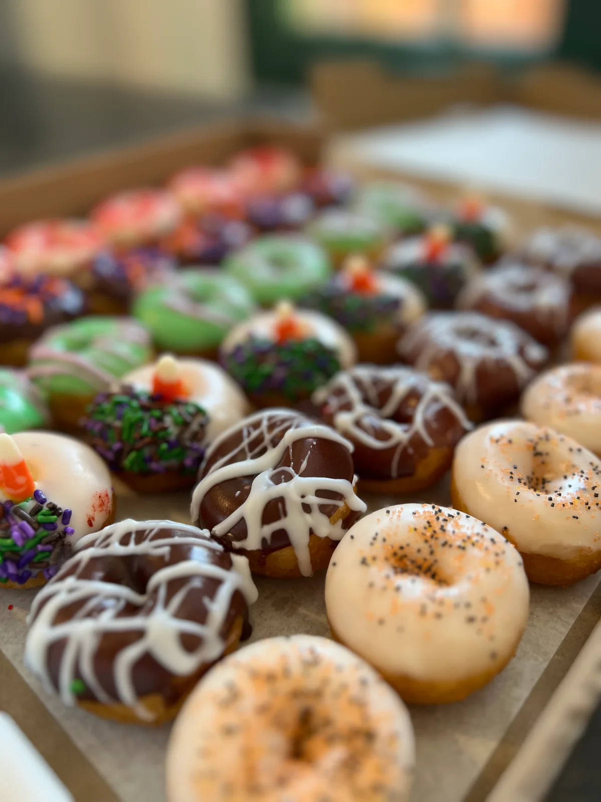 Close-up of The Mini Donut Company seasonal mini donuts with chocolate drizzle, speckled glaze, green icing, and candy corn toppings